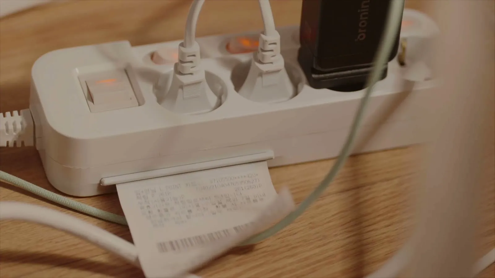 A receipt spooling out from under the plugs in a power strip